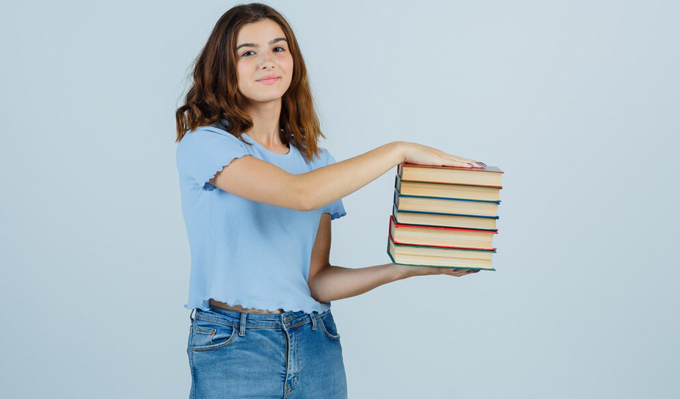 جمع‌ بندی کنکور | دانش آموز دختر با تعدادی کتاب در دست